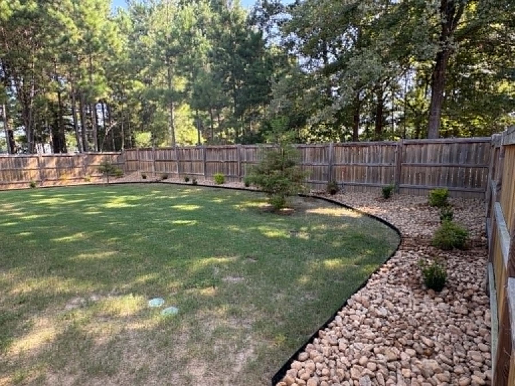 Decorative rock bed and new sod installed by Oakvera Outdoor Living in Madison, Mississippi
