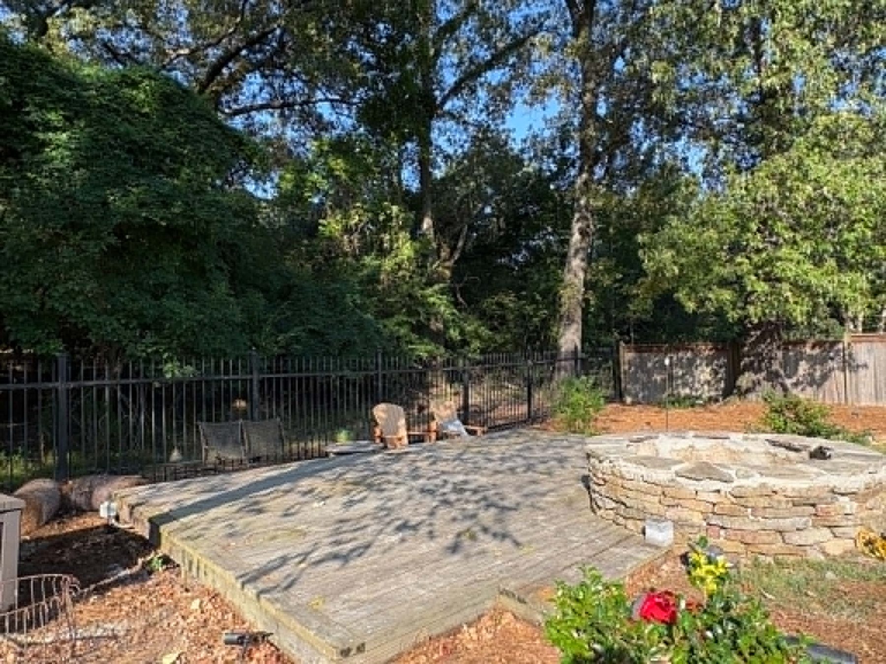 Before: weathered deck and an unfinished stacked stone fire pit with bare ground around it