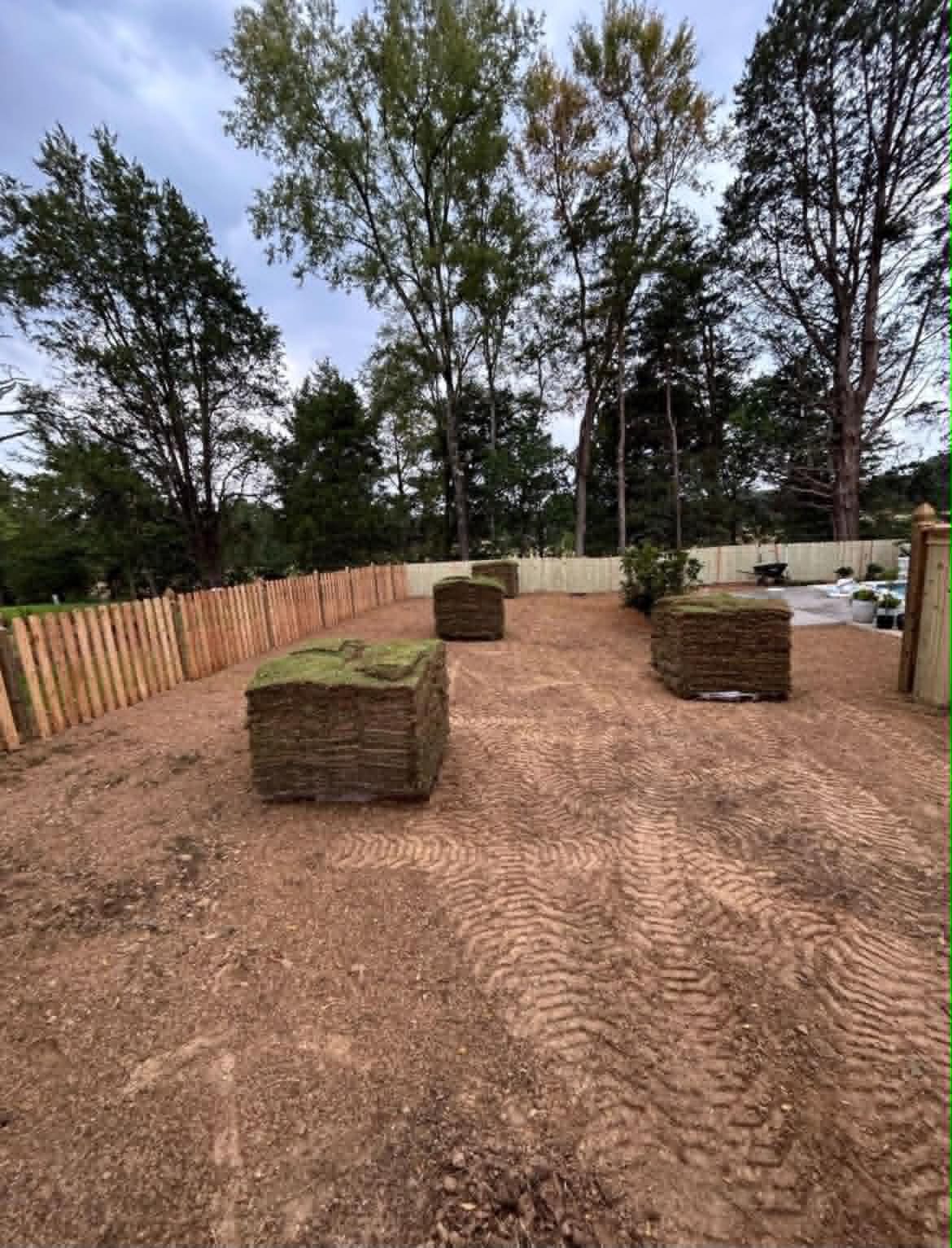 Sod Installation project by Oakvera Outdoor Living in Central Mississippi. Pallets staged on a freshly graded backyard, ready to lay behind a new fence line.