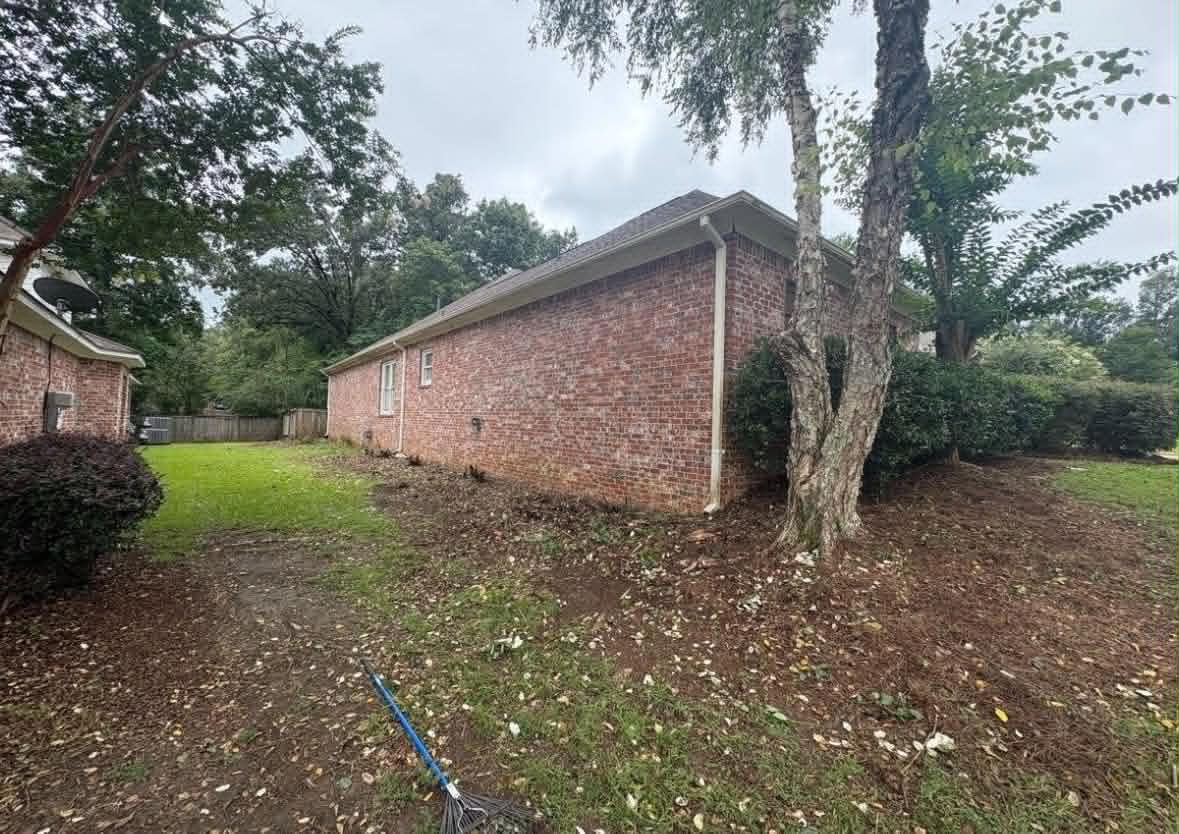 After: overgrowth removed and beds reshaped and edged along the same brick home