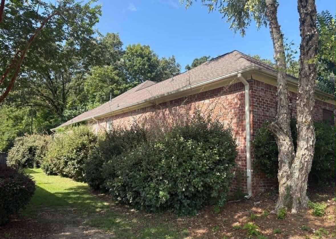 Before: overgrown shrubs crowding the foundation of a brick home